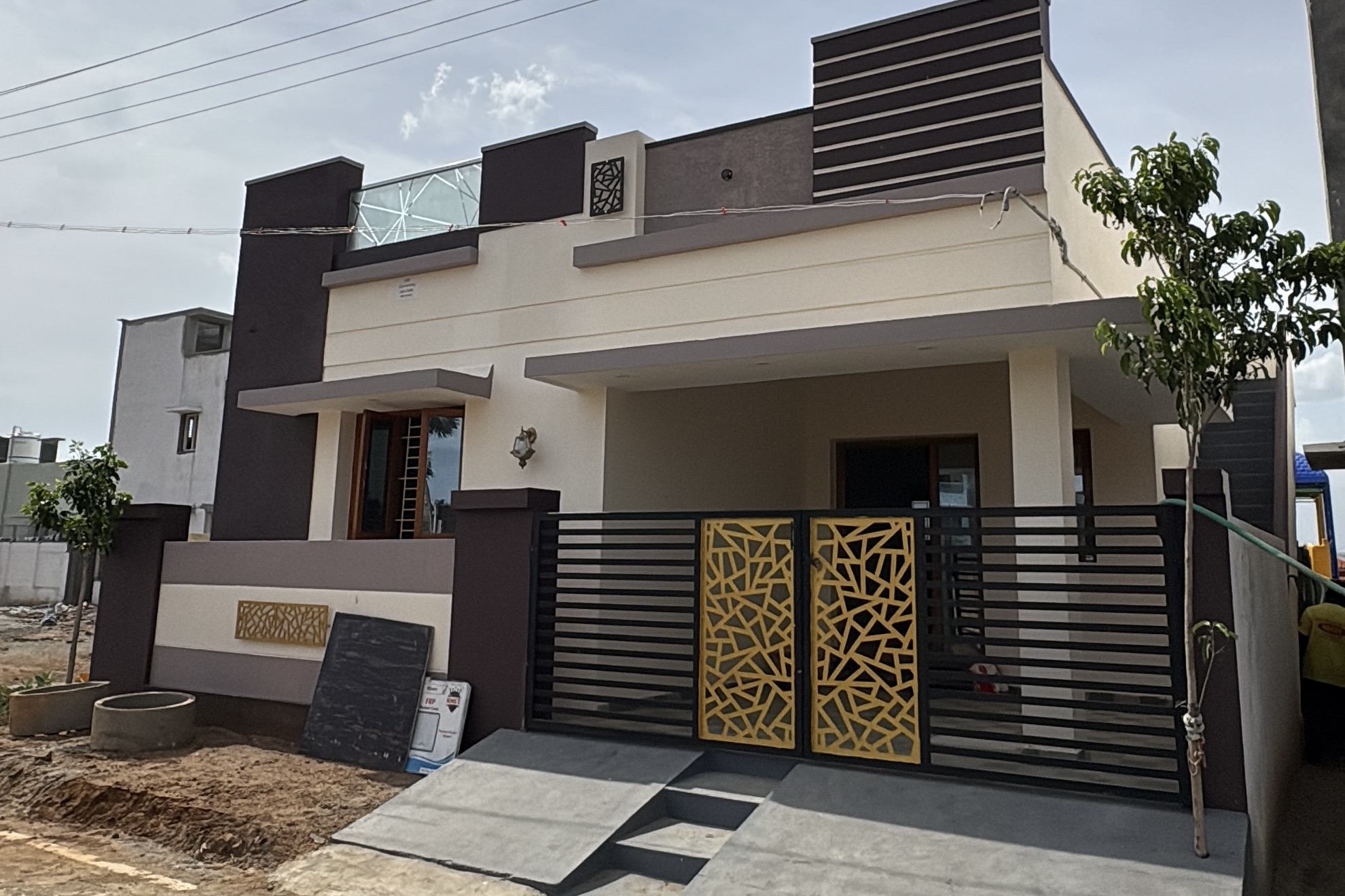 Completed single-storey home with a cream and brown elevation, laser-cut gold gate panels and a covered front verandah