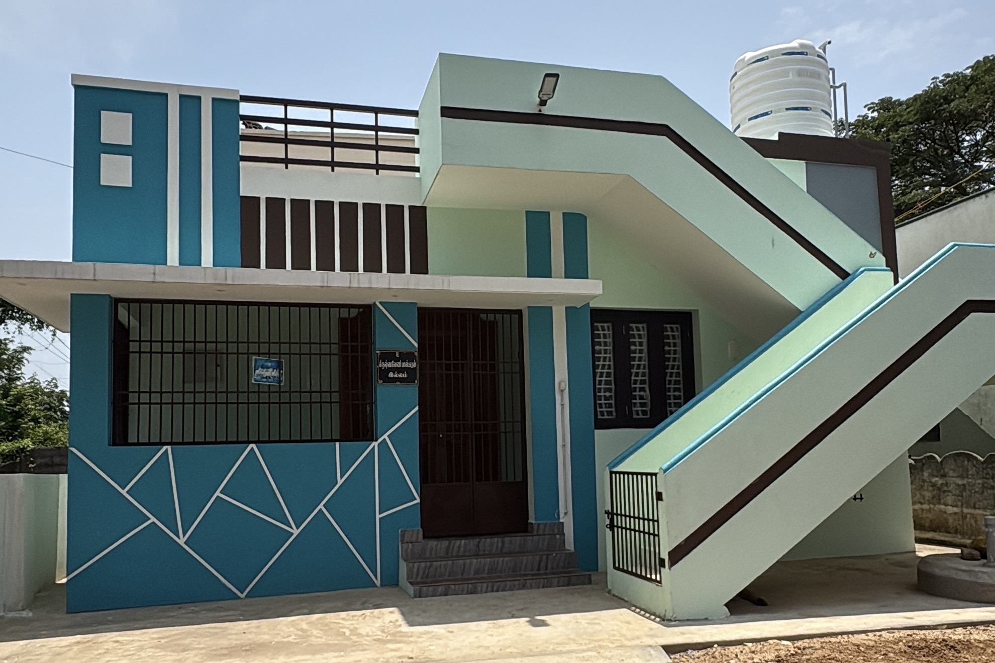 Completed compact home with a blue and mint geometric elevation and an external staircase to the terrace